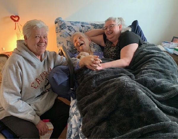 A woman wearing a sweatshirt that says california is sitting next to two other women