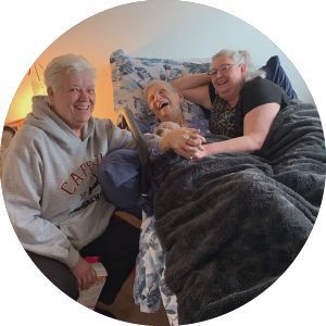 Three elderly women are sitting next to each other on a bed.
