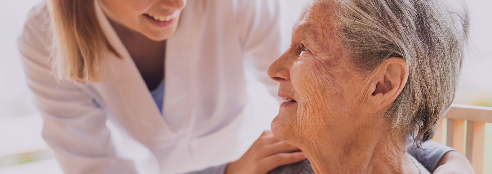 A nurse is talking to an elderly woman in a chair.