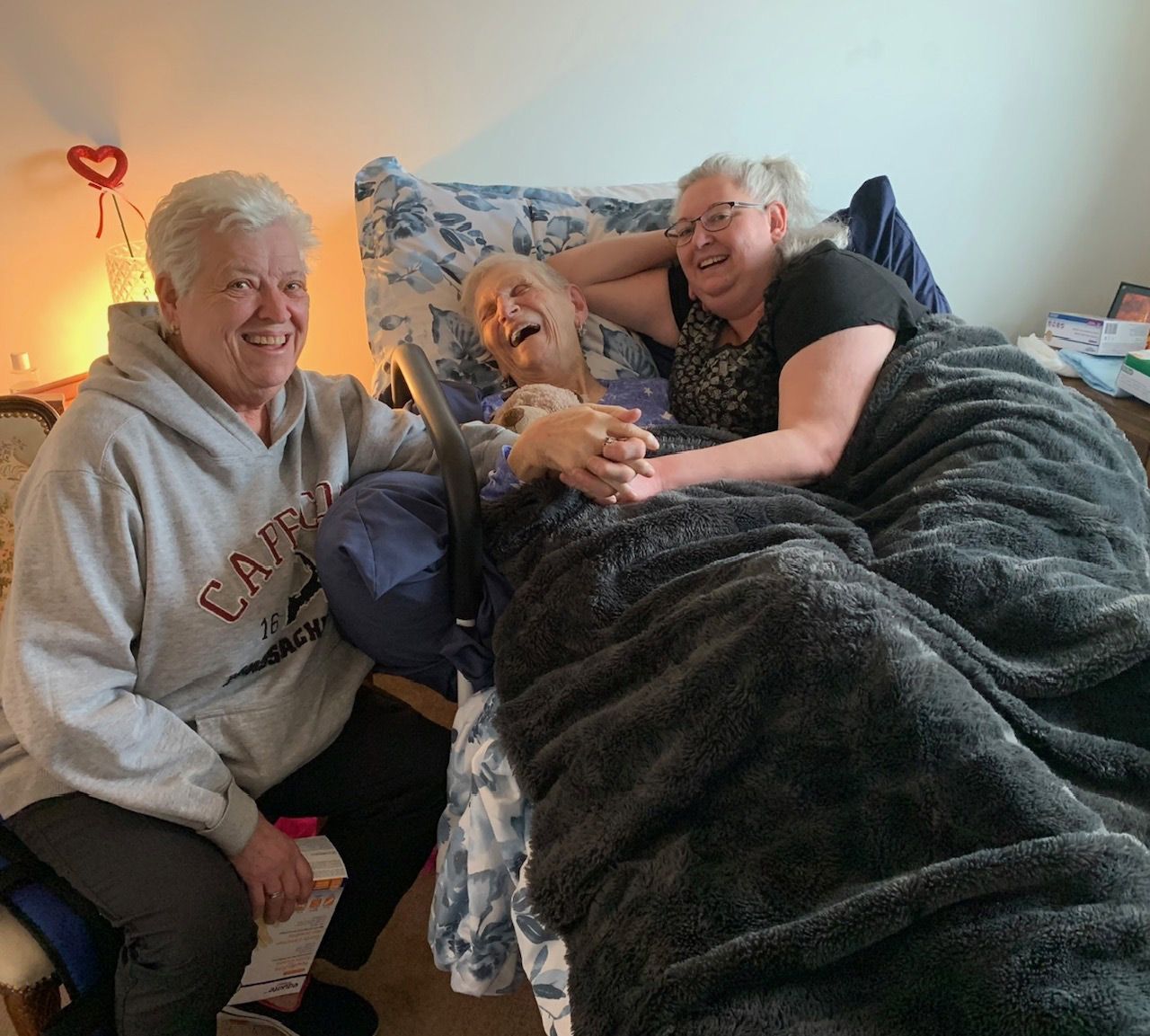 A woman wearing a camp sweatshirt sits next to two other women