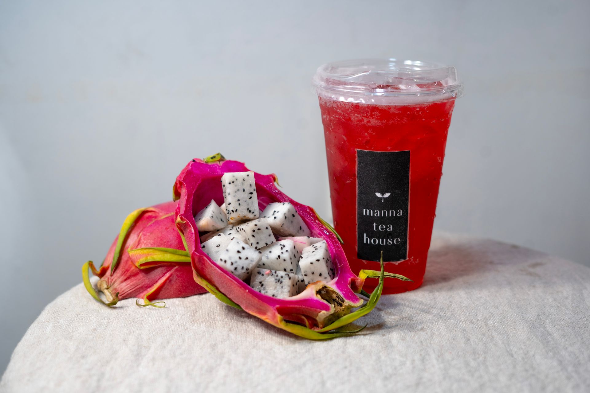 Dragon fruit on pink tissue beside a red drink cup on a white tablecloth.