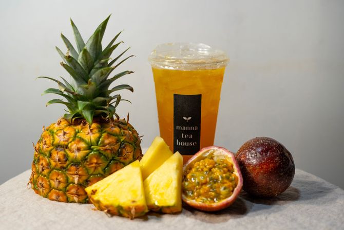 Pineapple and passion fruit beside a pineapple drink with pineapple slices on a gray surface