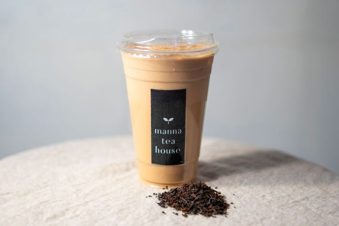 Iced coffee in a clear plastic cup with a black label, sitting on a light fabric surface.