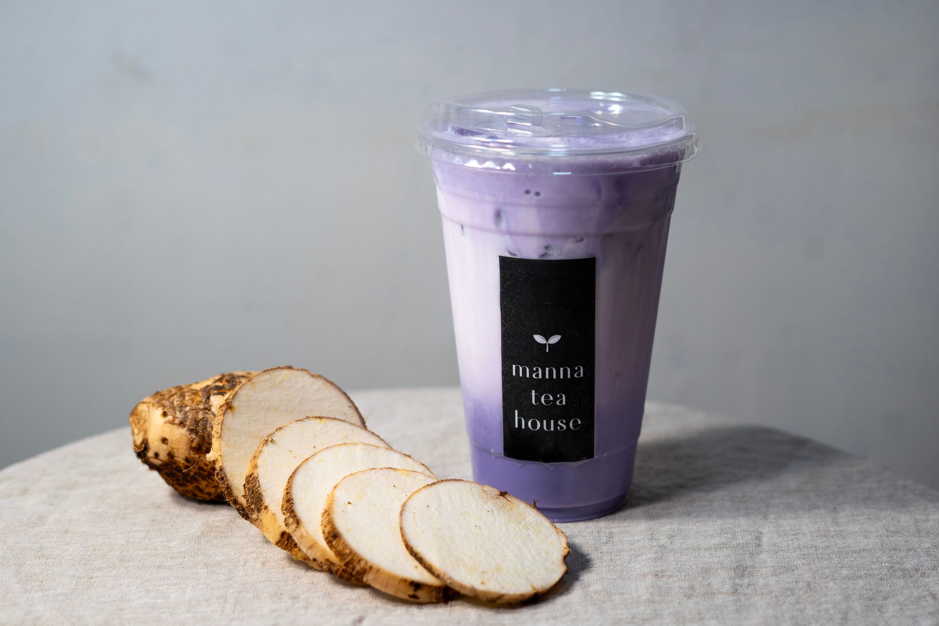 Purple smoothie in a clear cup beside sliced white bread on a gray surface