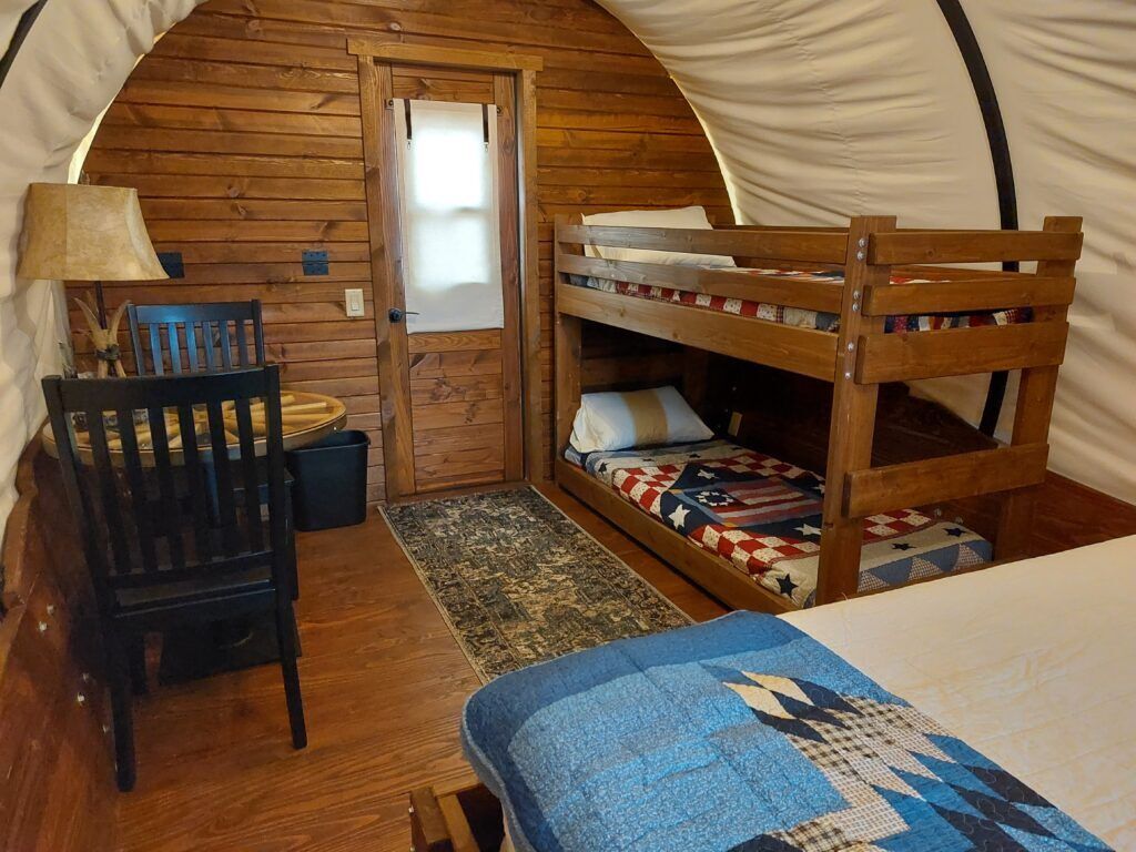 Cozy cabin bunk room with wood-paneled walls, two bunk beds, and a chair by the window.