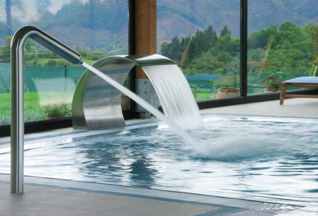 Dettaglio di una piscina con cascata d'acqua e vetrata sul retro