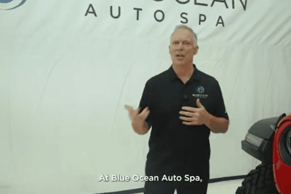 A Blue Ocean Auto Spa expert applies paint protection film to a car’s headlight with precision and care.