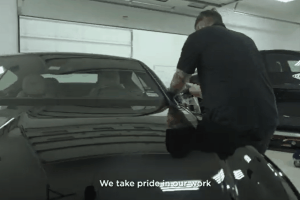 A Blue Ocean Auto Spa expert meticulously applies paint protection film to a sleek black car inside the detailing bay.