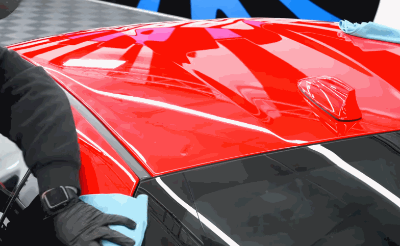 Heat gun used to shape paint protection film around a white vehicle door handle and body panel edge.