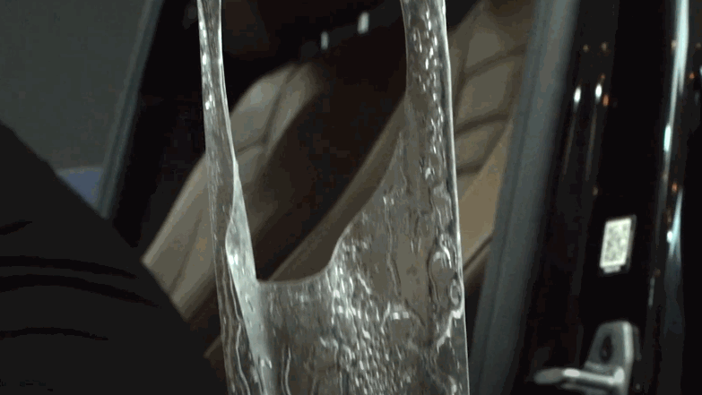 A gloved hand opens the rear hatch of a black car, showcasing the glossy finish and clean lines after ceramic coating application.