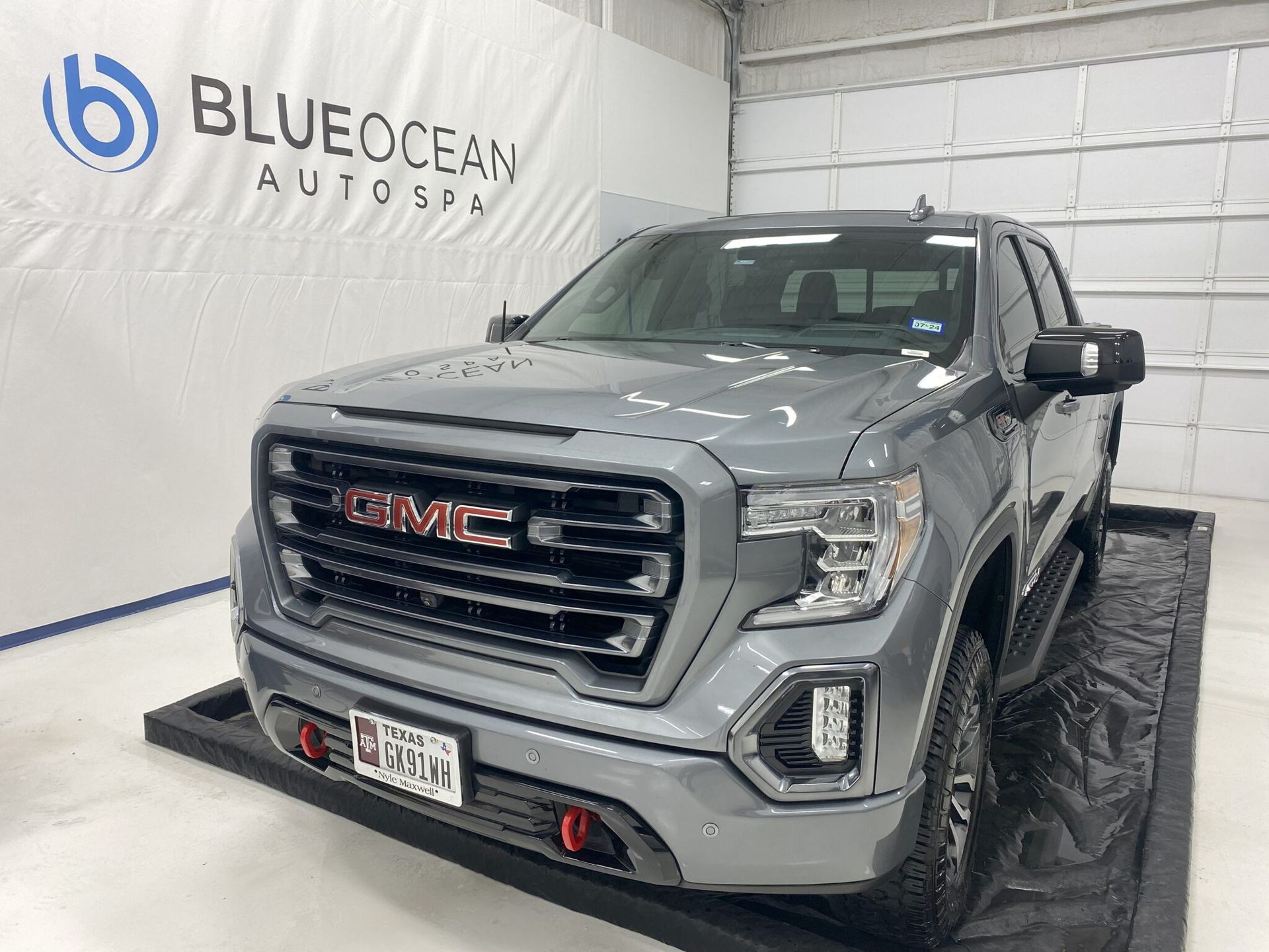 A gray gmc sierra 1500 truck is parked in a showroom.