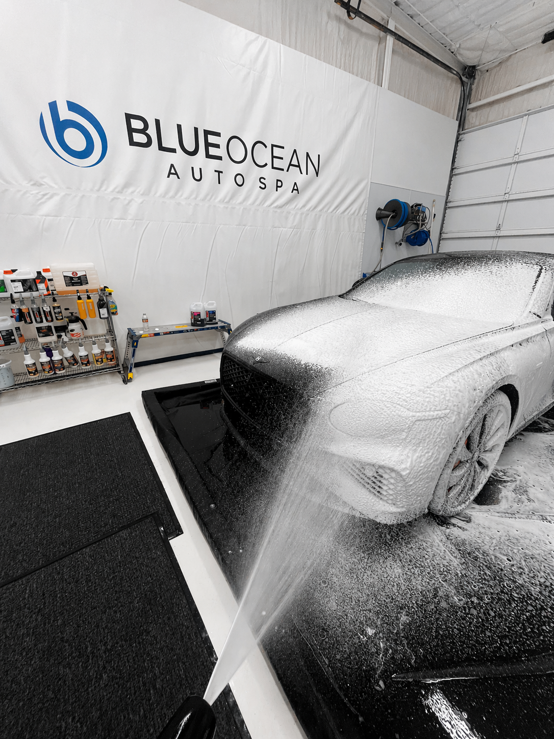 A 2025 Bentley Continental GT Black Edition front bumper and hood are being sprayed down with a gental snow foam to loosen dirt and grime on the car and in hard to reach girlle details.