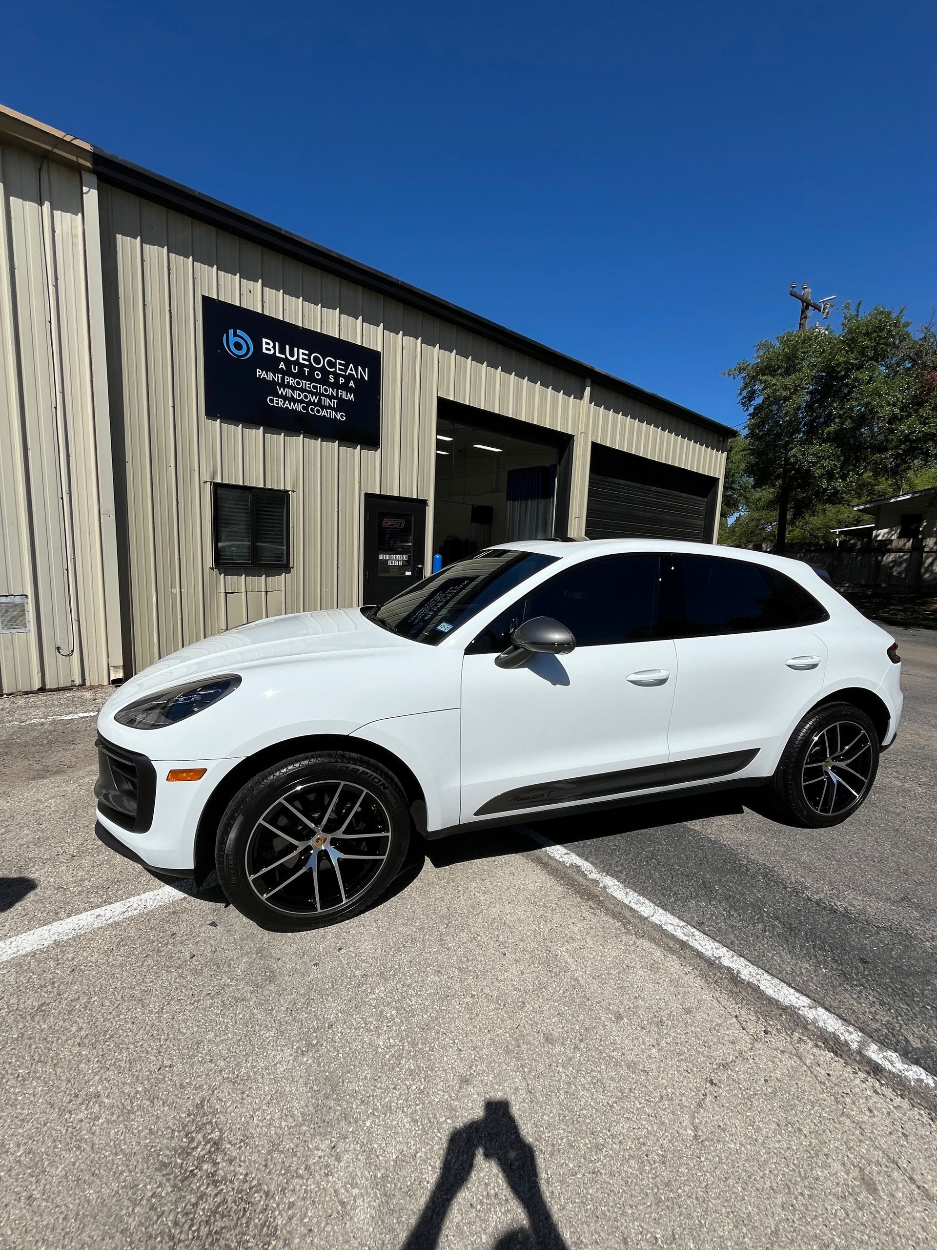 A 2025 Porsche Macan outside and in front of Blue Ocean Auto Spa of Cedar Park Texas and showing how it has a deep gloss after being ceramic coated.
