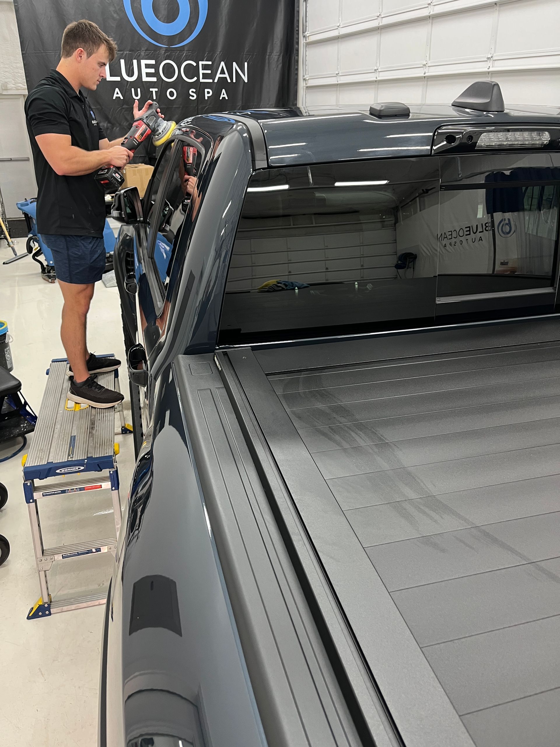 A technician is using a dual action polisher to remove micro-scratches from the clear coat and create more gloss in the paint.