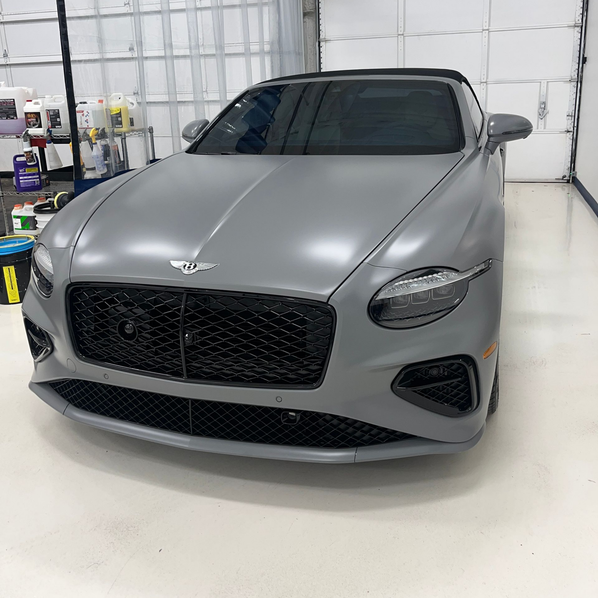 Gray Bentley car in a garage with black grill and tinted windows.