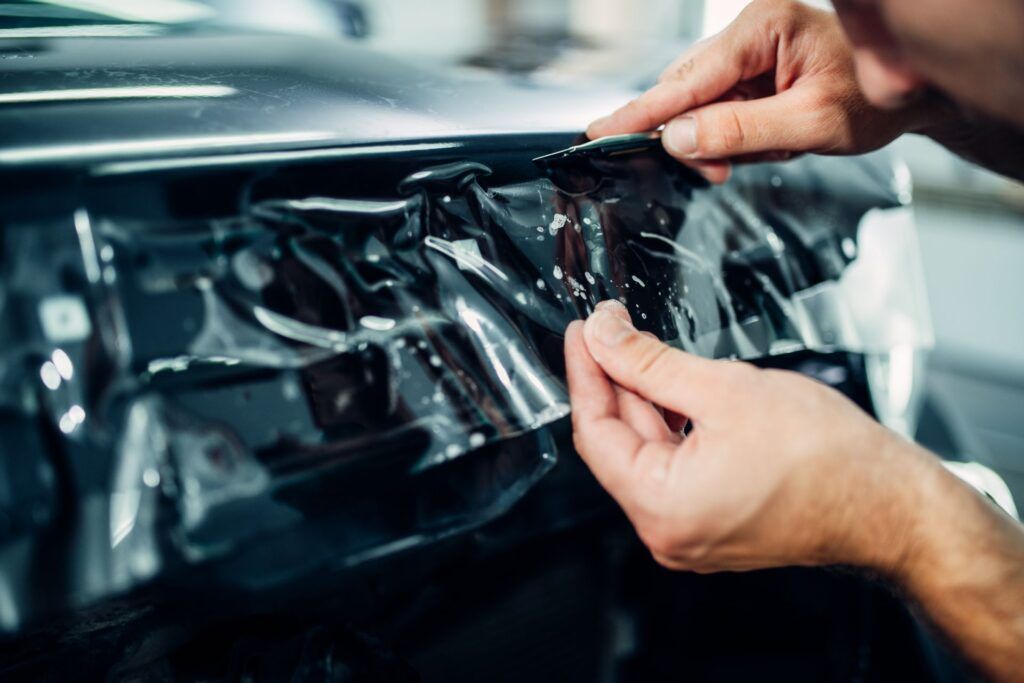 A man is applying a protective film to the dashboard of a car.