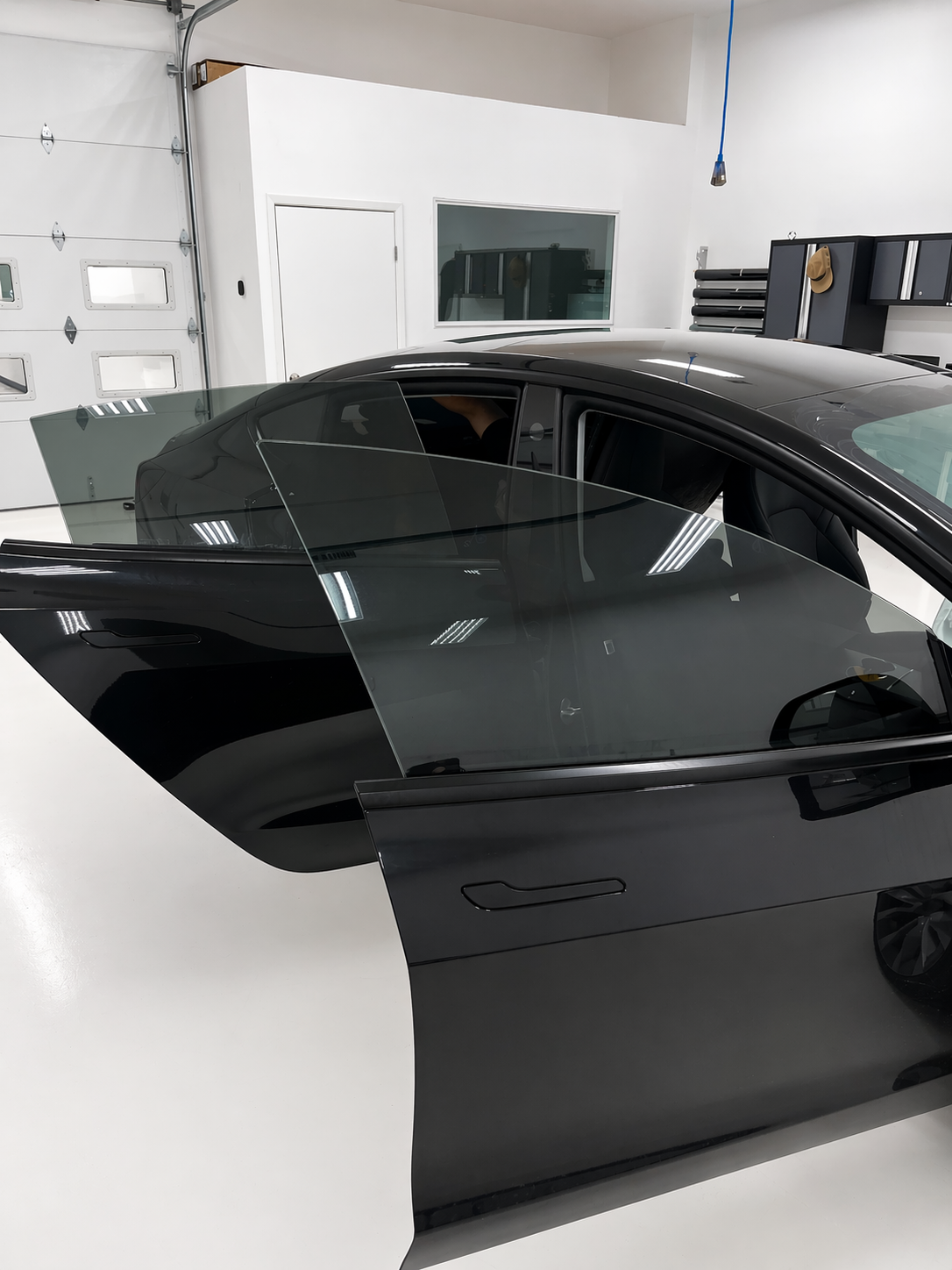Tesla Model 3 inside the Blue Ocean Auto Spa tinting clean room shown with doors open to highlight the tint shade after being tinted with XPEL PRIME XR PLUS ceramic window film.
