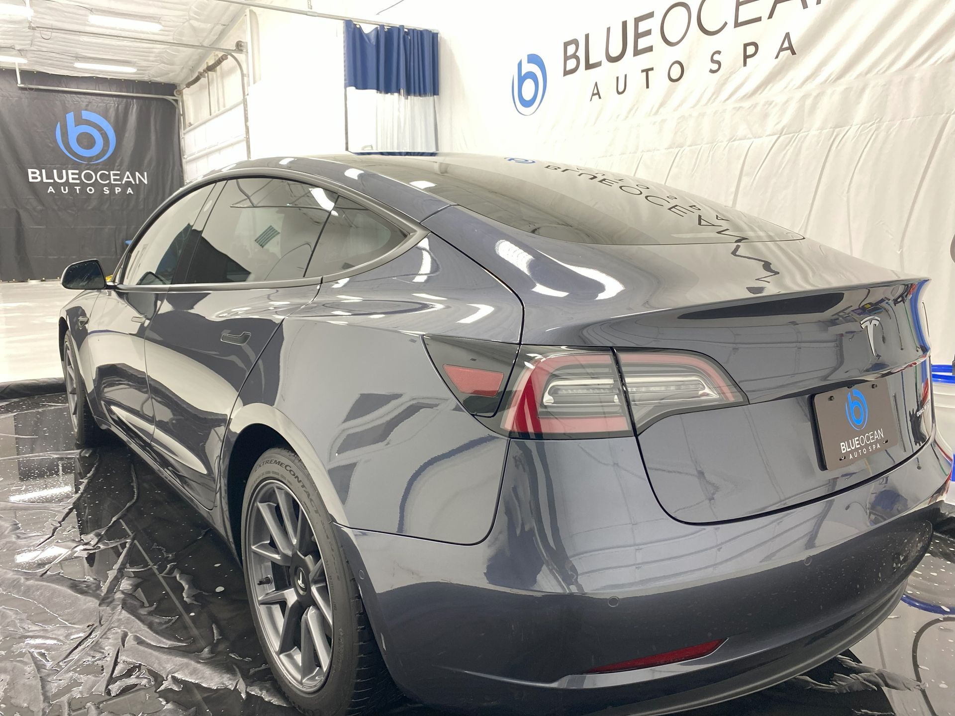 The rear end of a tesla model 3 is shown in a garage.