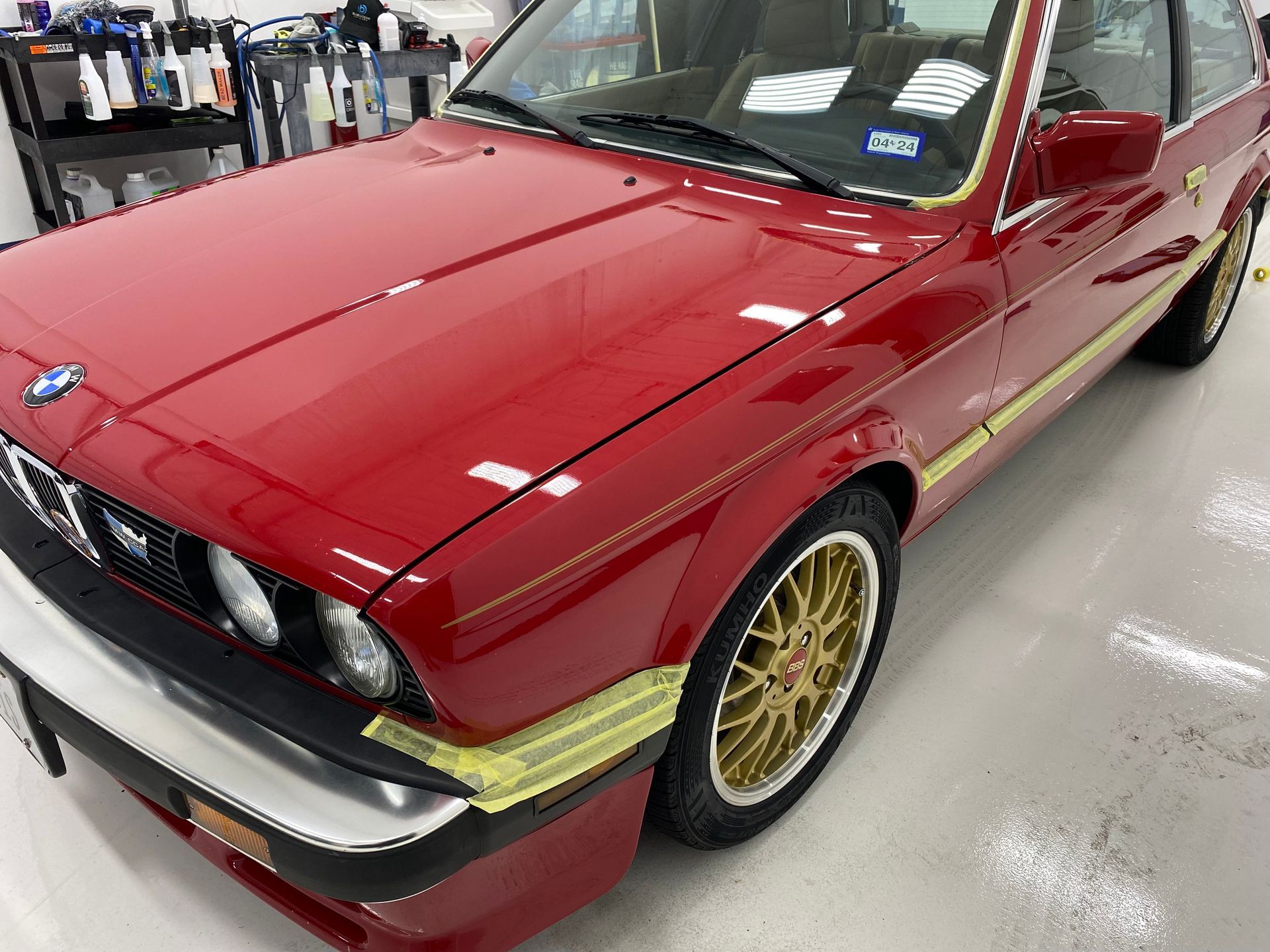 A red car with gold wheels is parked in a garage.