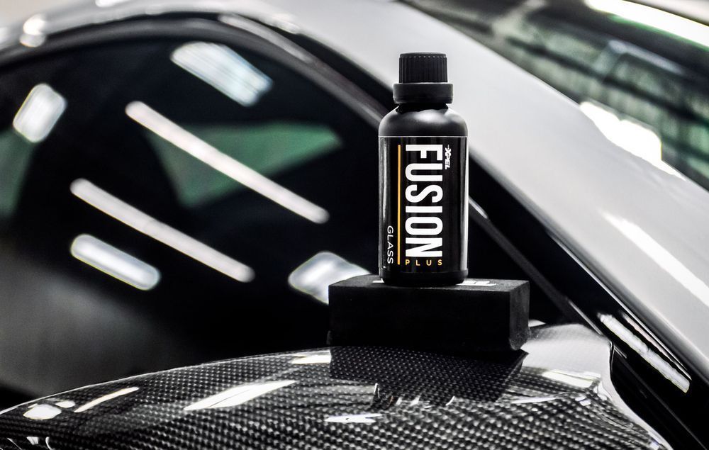 A bottle of fusion is sitting on top of a car.