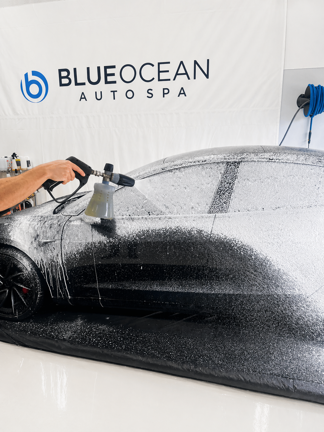 Installer uses a heat gun on window tint film applied to a car door, helping the material conform smoothly to the glass surface. The tint darkens the window while reflections of the workspace remain visible.