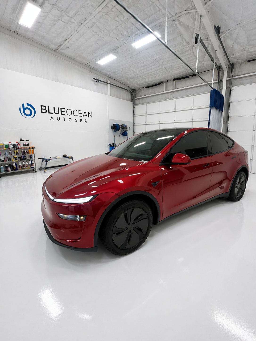 A window tint technician applies ceramic window tint to the front door window of a Tesla Model Y in a clean room at Blue Ocean Auto Spa of Cedar Park Tx