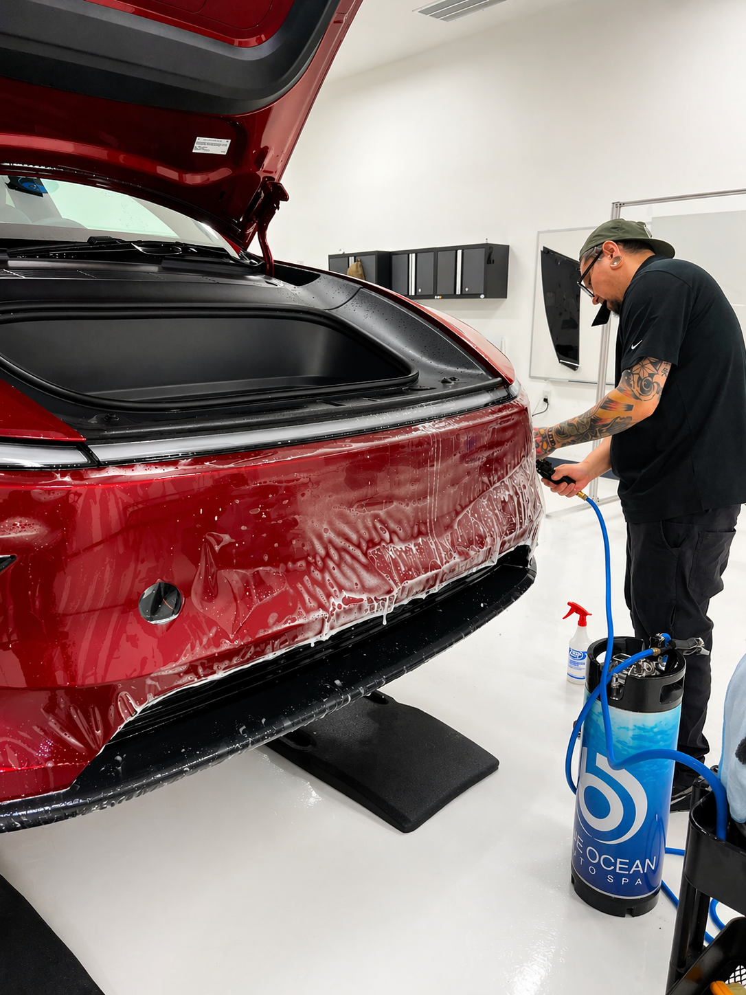 Our technician sprays slip solution on the front bumper of a Tesla Model Y as they align the paint protection film before locking down the PPF.