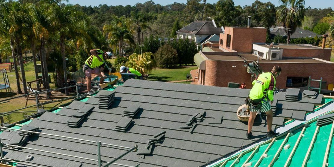 A Group of Construction Workers Are Working on the Roof of a House — Mr Roof Tiles in Kingscliff, NSW