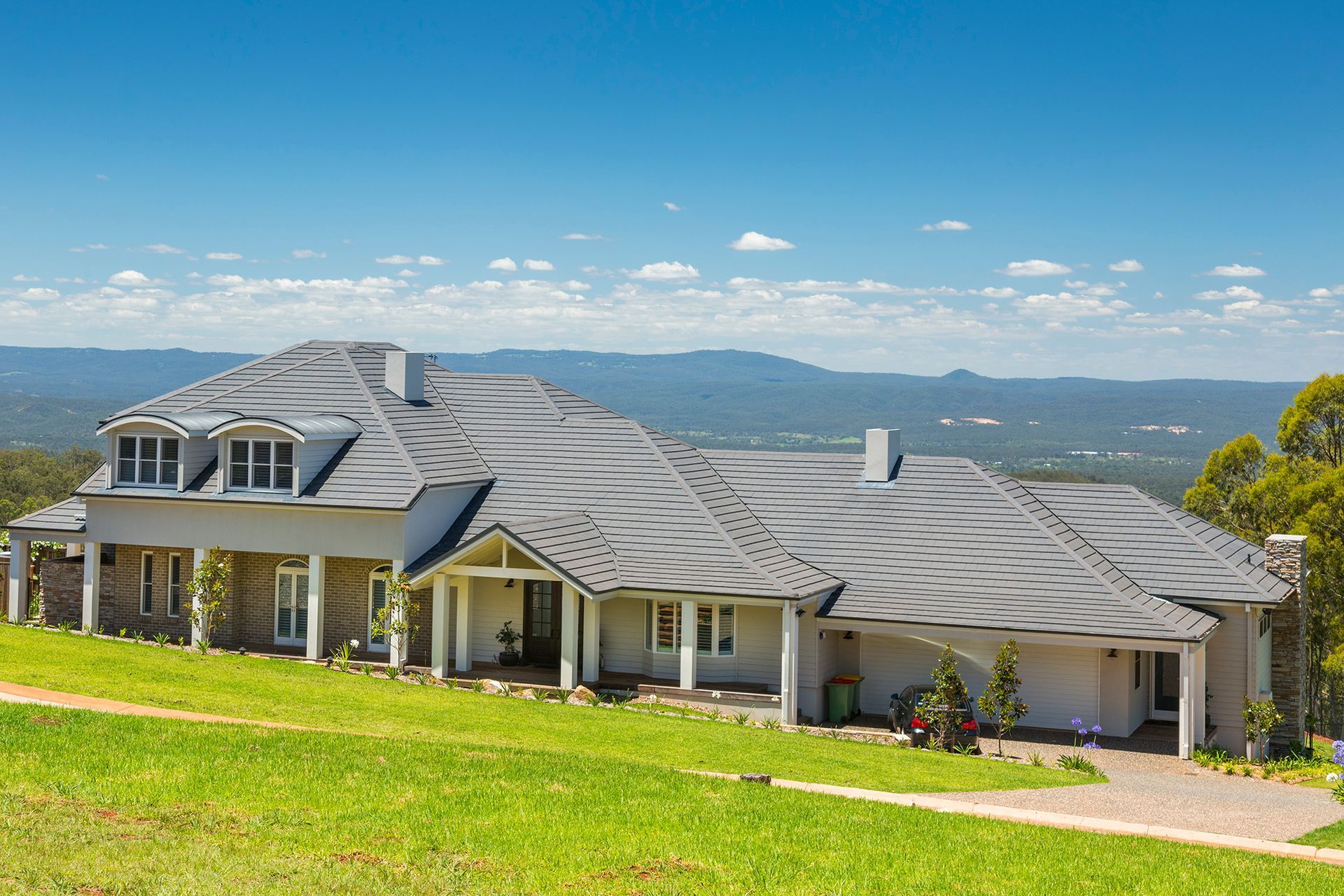 A Large House is Sitting on Top of a Grassy Hill — Mr Roof Tiles in Northern Rivers, NSW