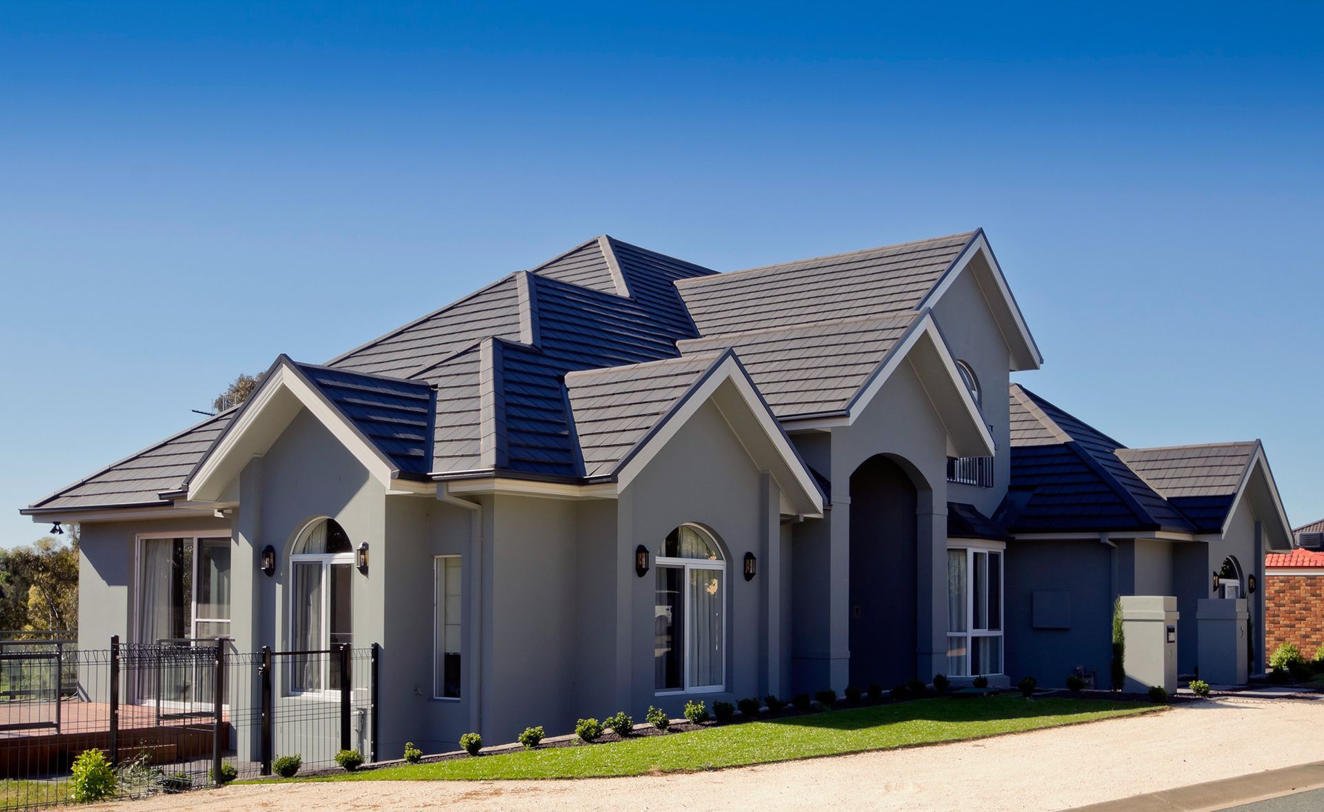 A Large House With a Gray Roof and a Blue Sky in the Background — Mr Roof Tiles in Grafton, NSW