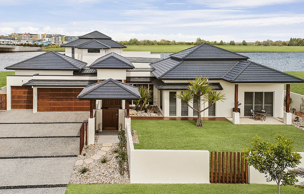 A Large White House With a Black Roof Sits Next to a Body of Water — Mr Roof Tiles in Murwillumbah, NSW
