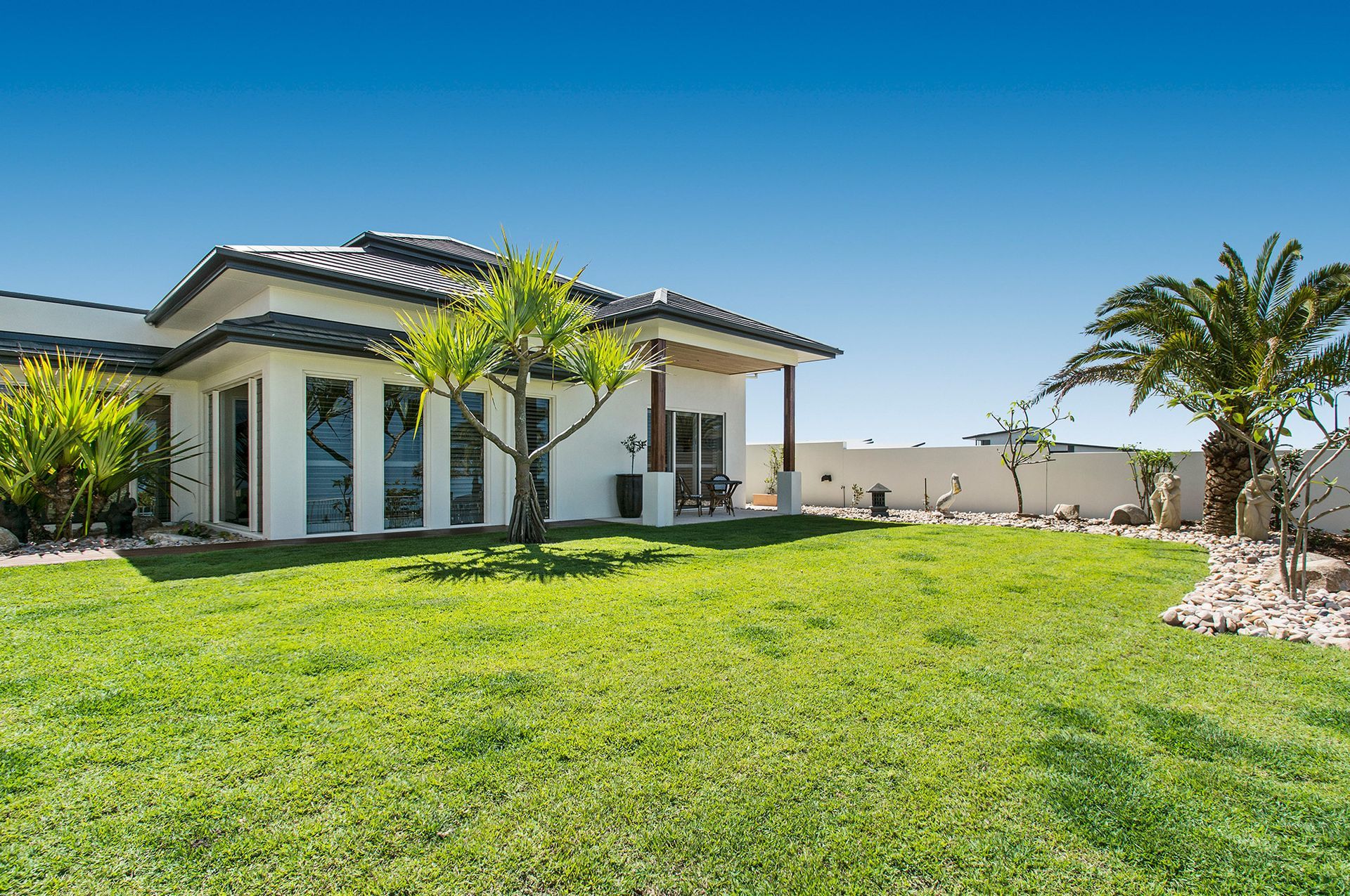 A Large White House With a Lush Green Lawn in Front of It — Mr Roof Tiles in Lismore, NSW