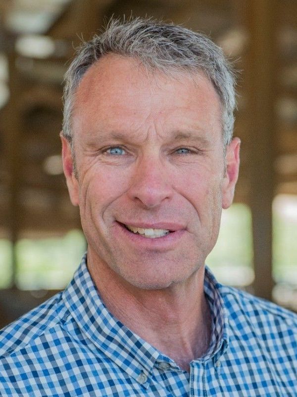 A man in a blue and white checkered shirt is smiling for the camera.