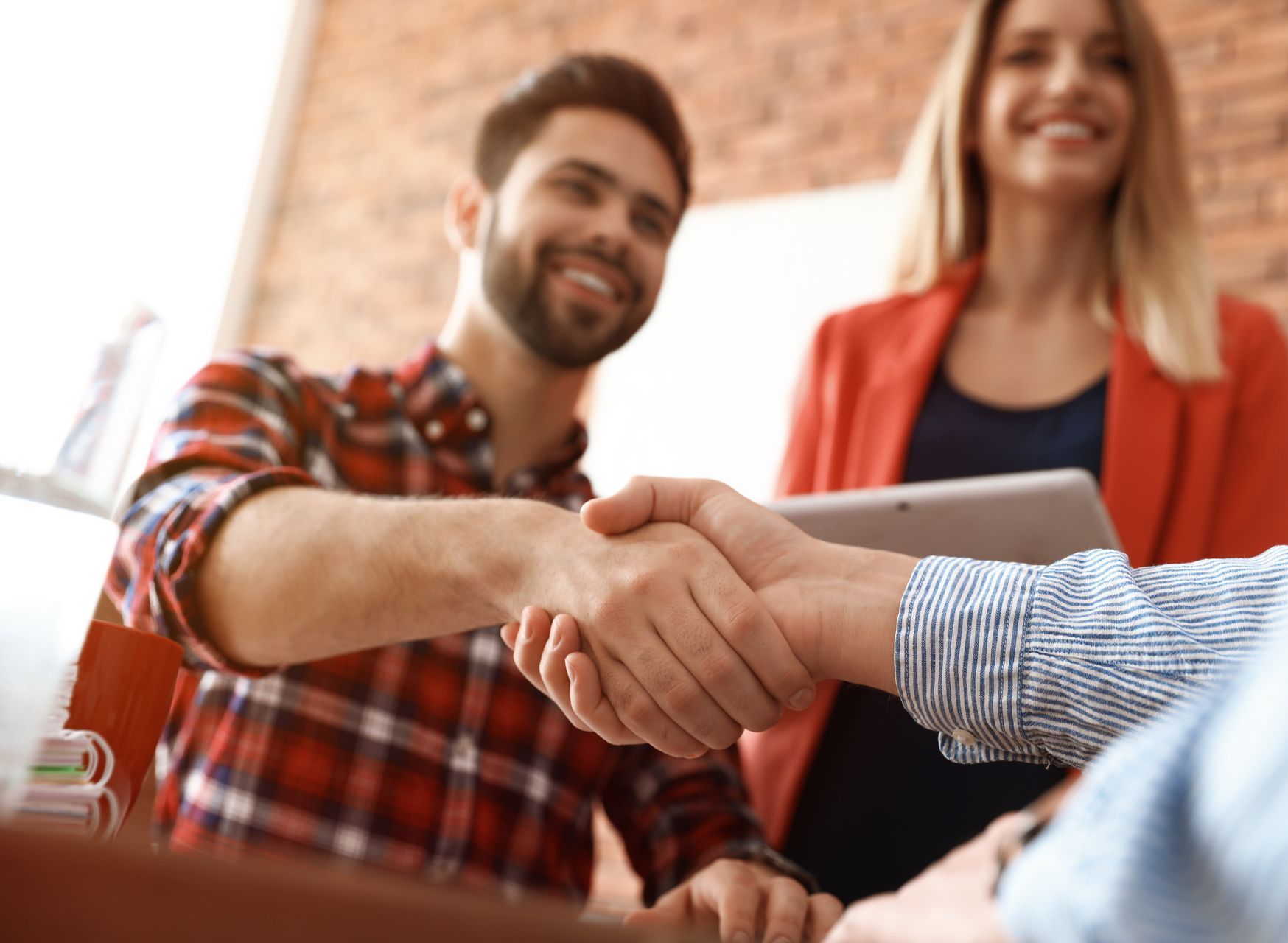 A man and a woman are shaking hands while sitting at a table.