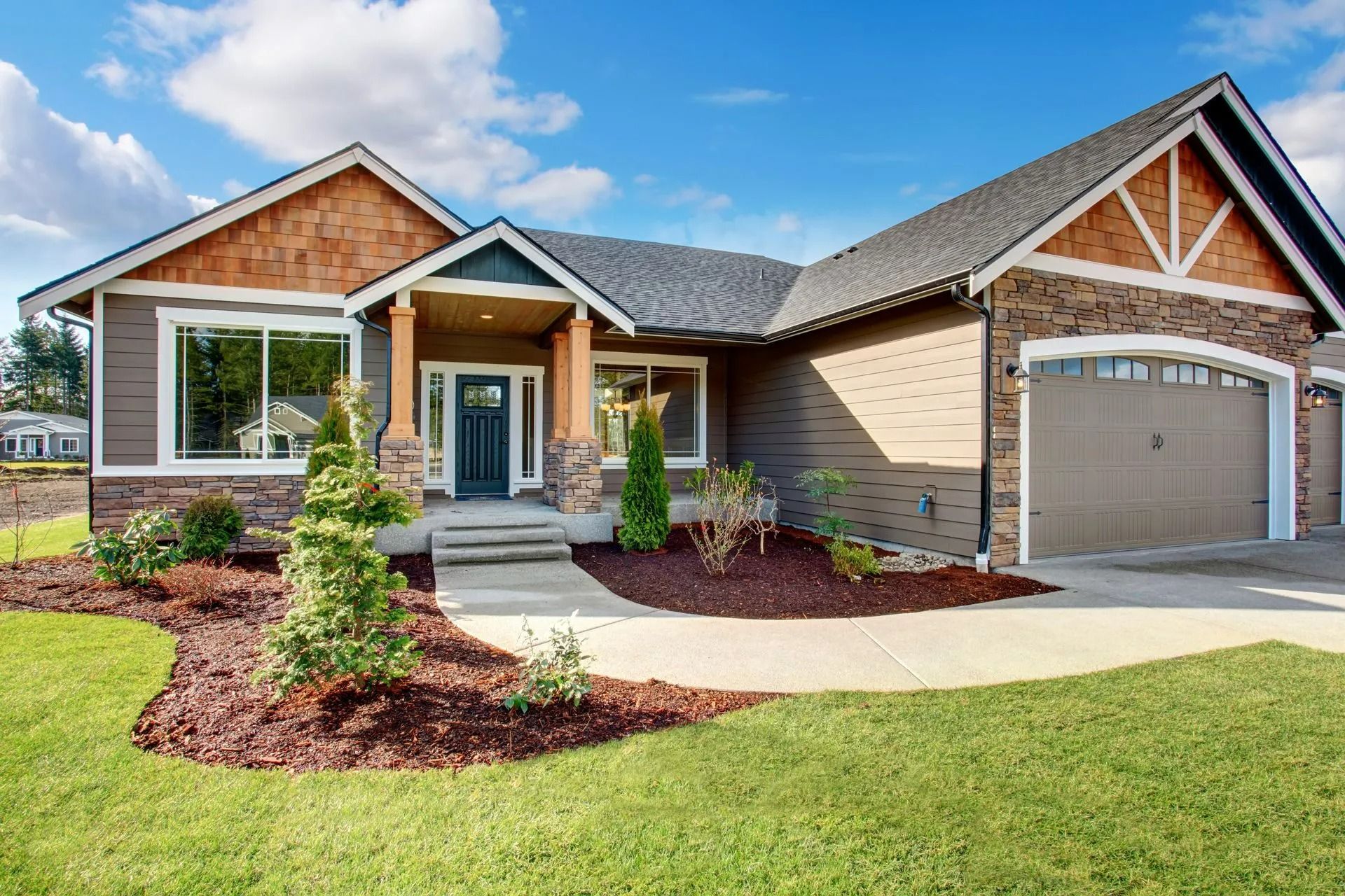 Single-story suburban house with stone and wood exterior, front porch, garage, and landscaped yard