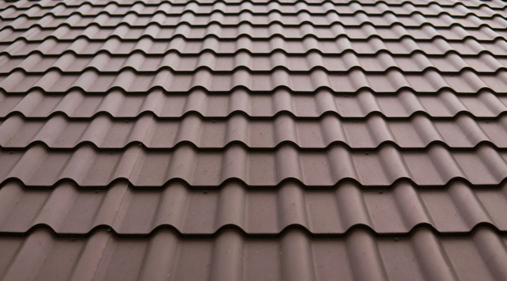 Brown tiled roof with repeating wavy shingles viewed from above