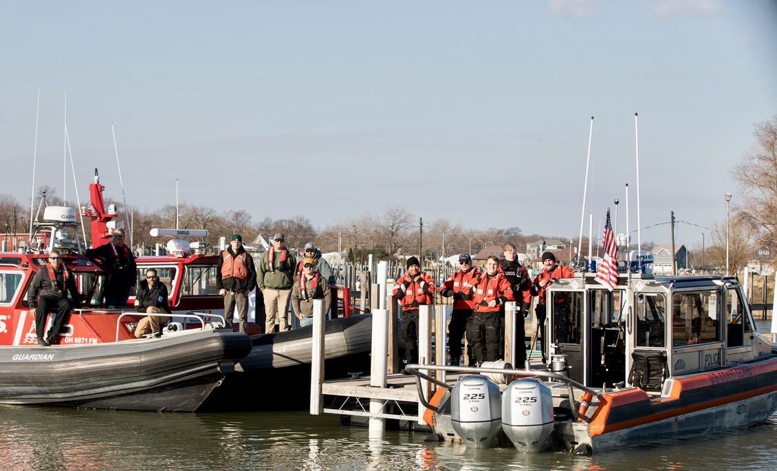 Volunteers in red jackets on boats at a dock, with pumps and equipment during a flood rescue operation.