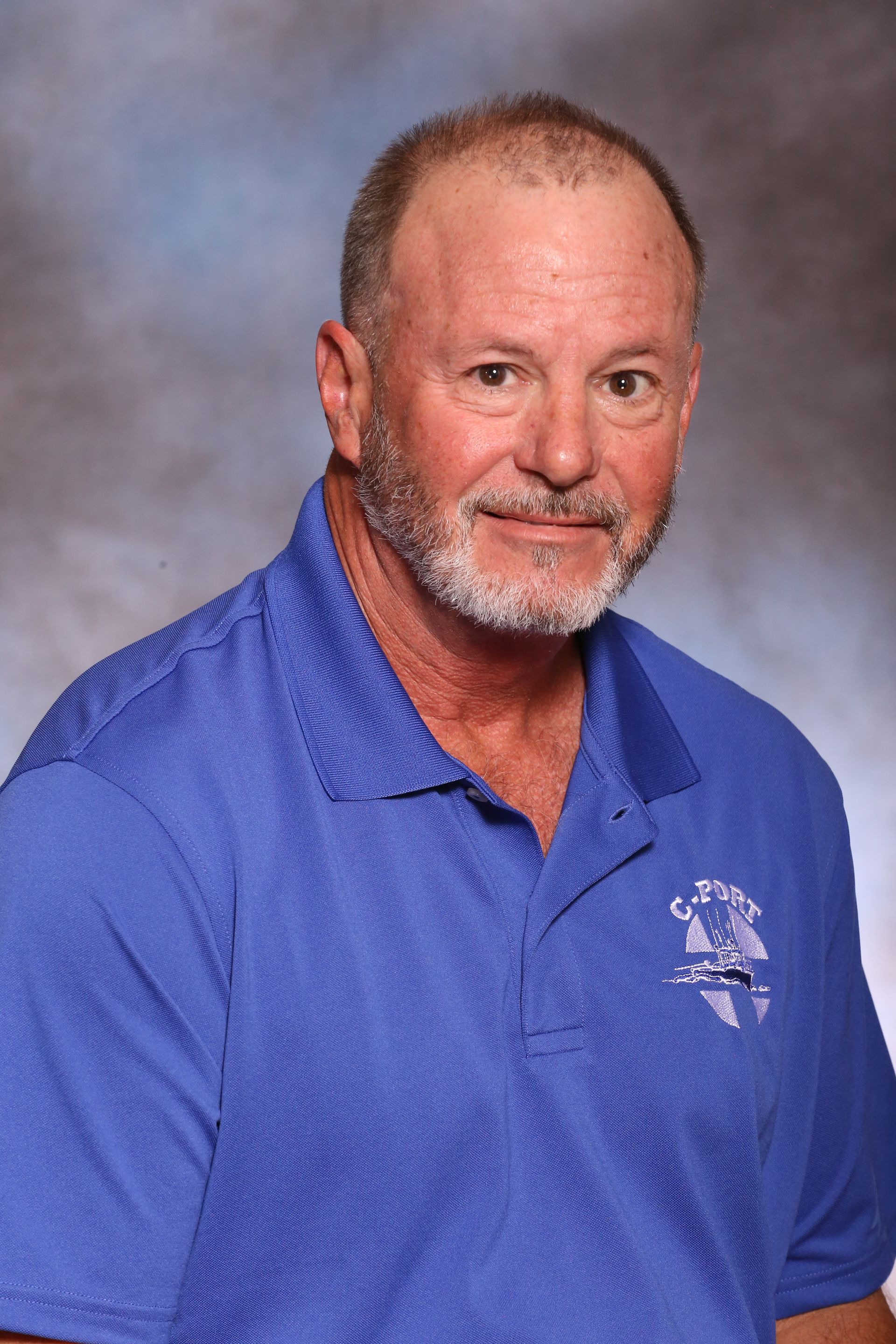 Man in a blue polo shirt posing against a gray studio backdrop