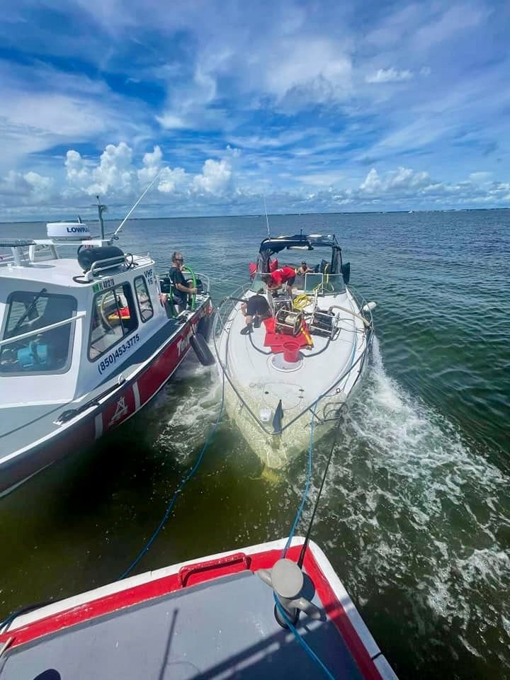 Two boats alongside a white speedboat on open water under a cloudy blue sky