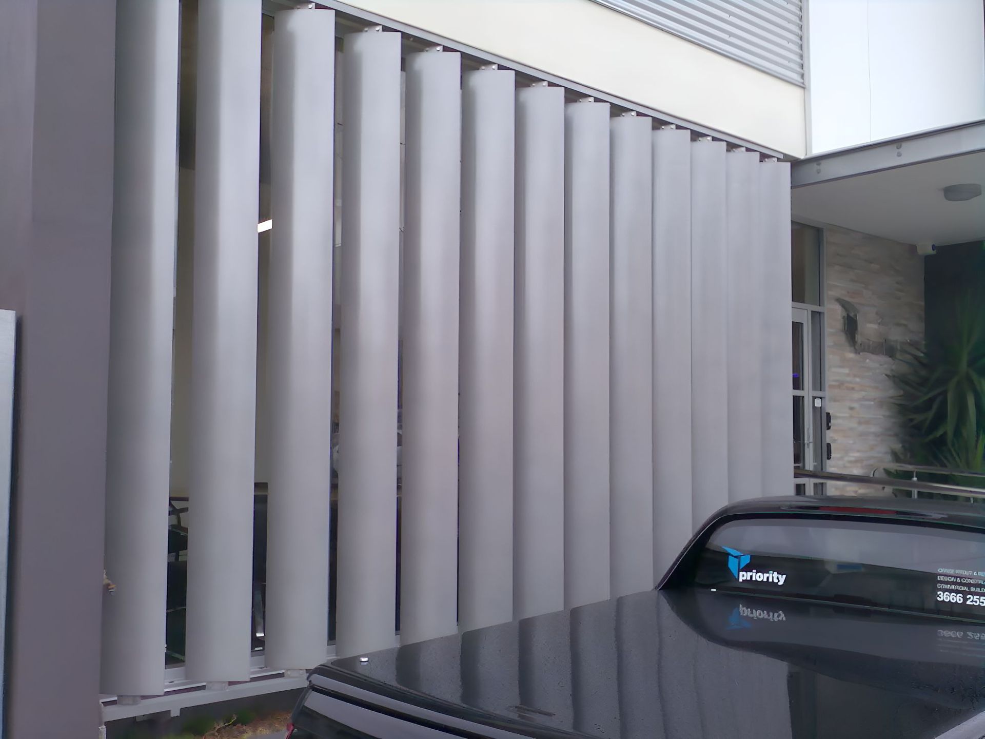 A Black Car is Parked in Front of a Building With a Gray Fence — South Burnett Garage Doors In Kingaroy, QLD