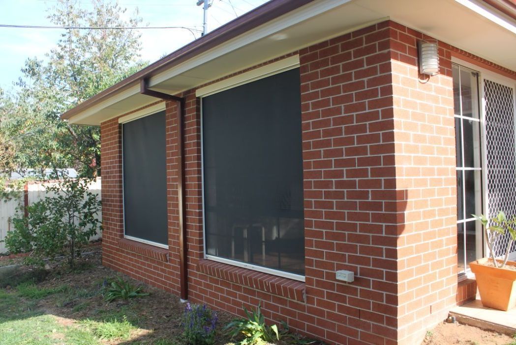 A Brick House With a Screen on the Windows — South Burnett Garage Doors In Murgon, QLD