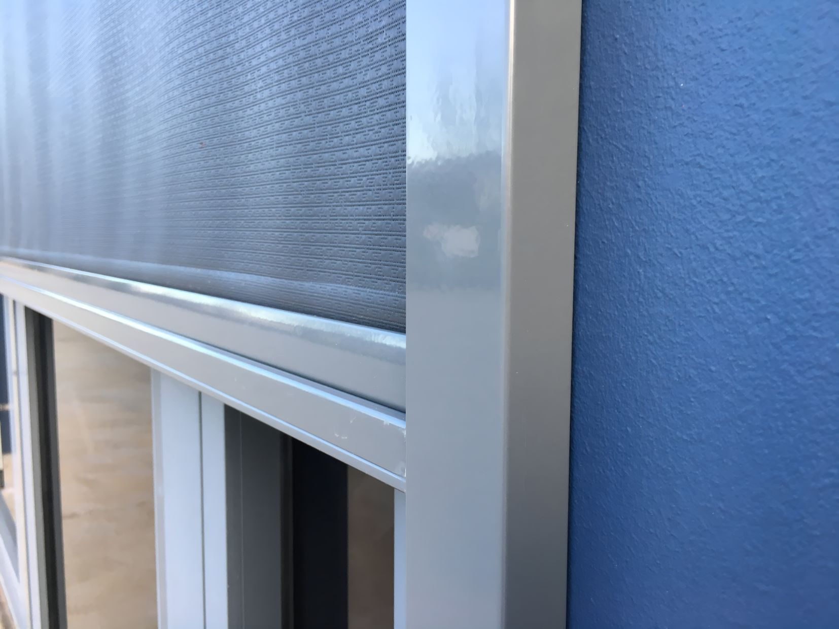 A Close Up of a Window With a Screen on It Against a Blue Wall — South Burnett Garage Doors In Yarraman, QLD
