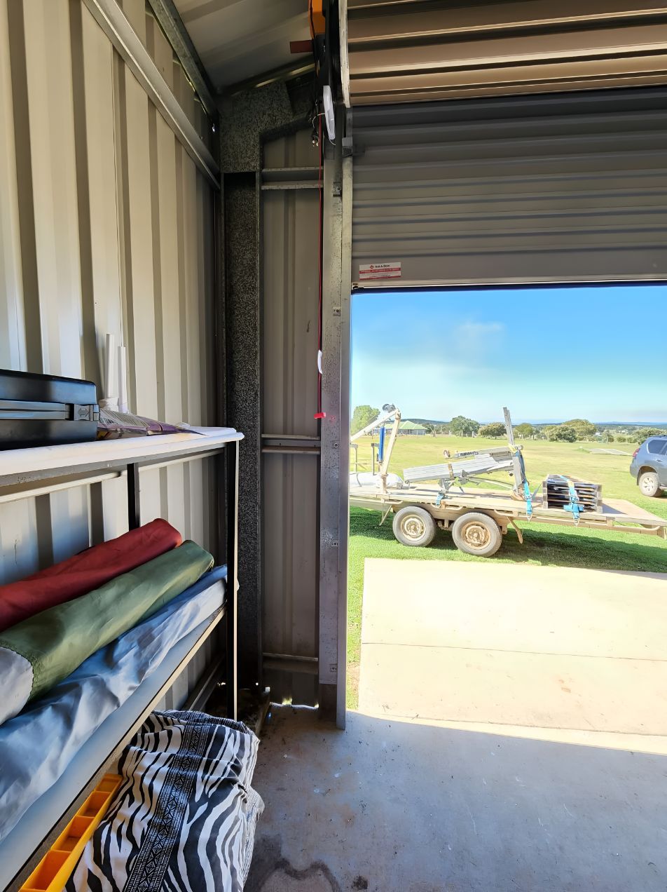 A Garage With a Roller Door Open and a Trailer Parked in the Background — South Burnett Garage Doors In Kingaroy, QLD