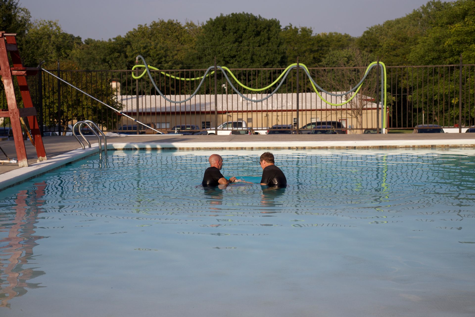 Two men are standing in a swimming pool.