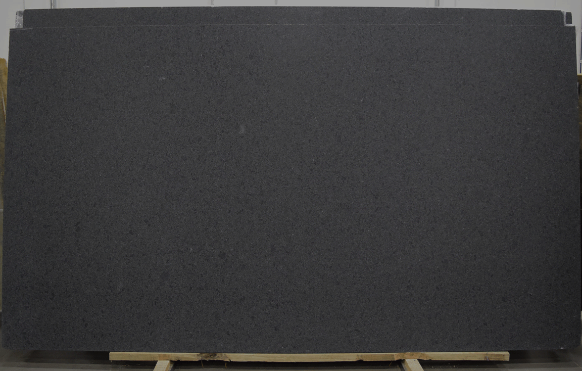Dark gray granite slab, likely for countertop use, displayed in a warehouse.