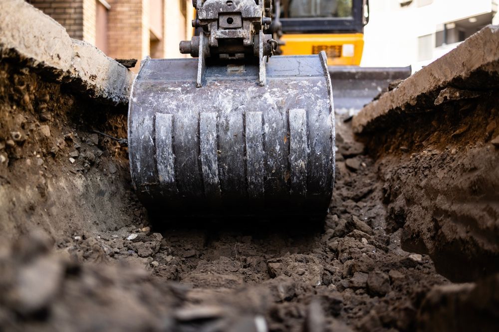 Excavator bucket in a trench, digging up dirt.
