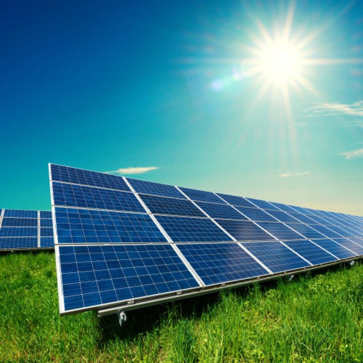Solar panels in a sunny green field under a bright blue sky