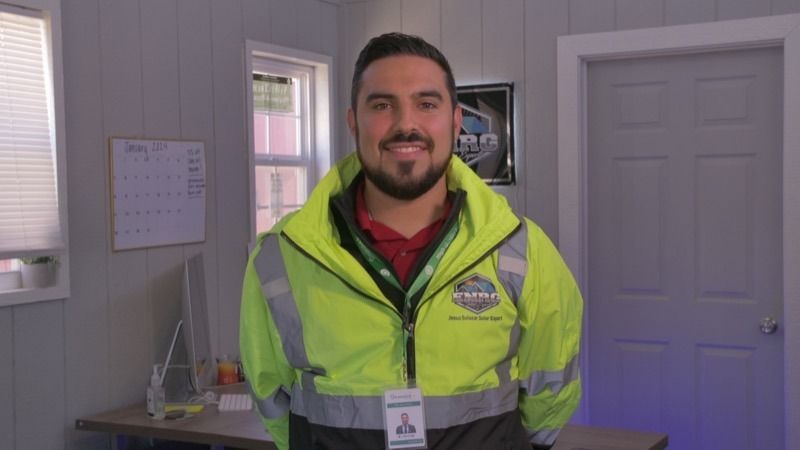 Man in a neon safety jacket smiling in an office hallway