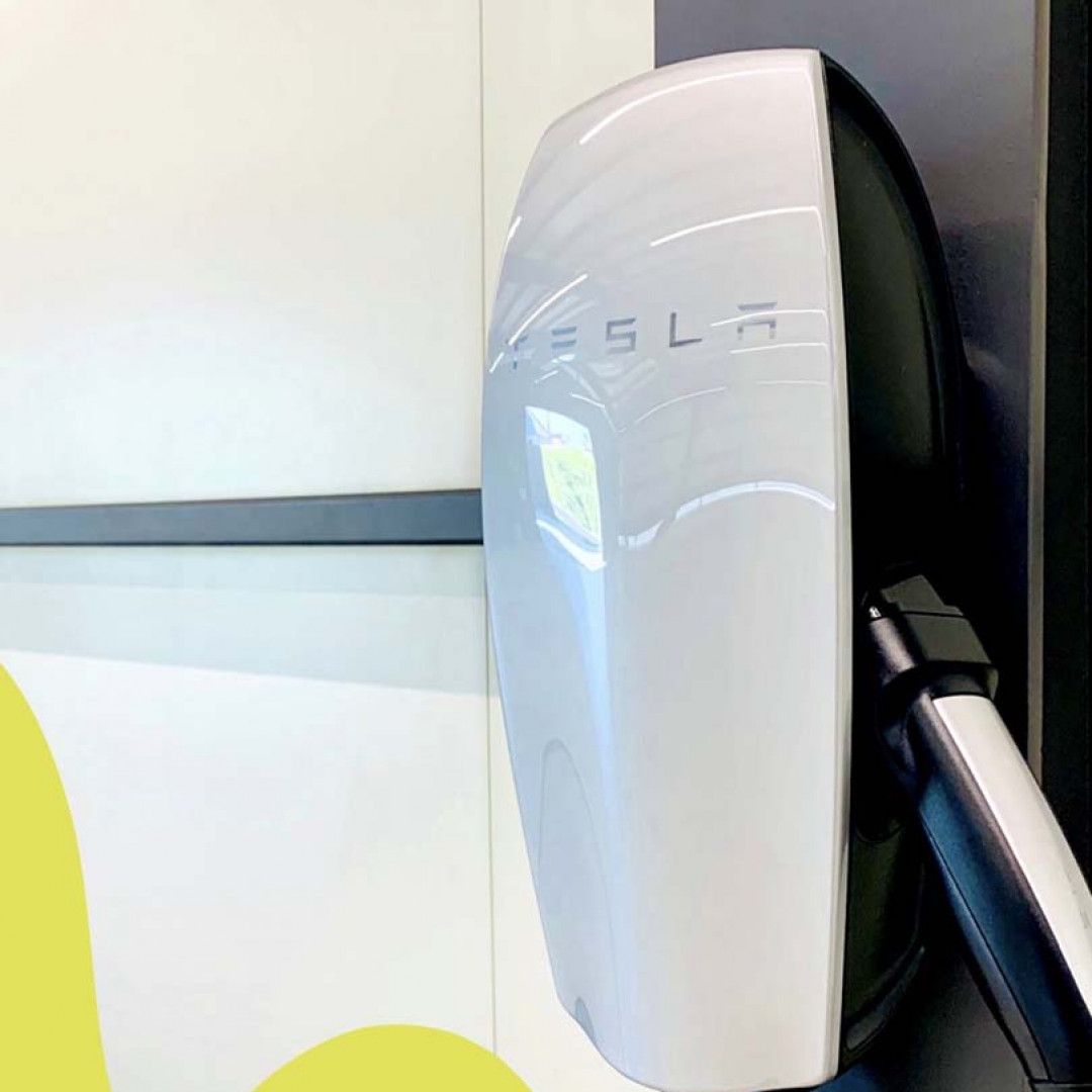 Tesla charging station with a plugged-in cable indoors