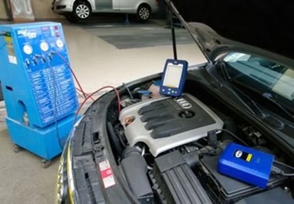 Vano motore di un'Audi con un'apparecchiatura blu per la manutenzione dell'aria condizionata collegata in un'officina.